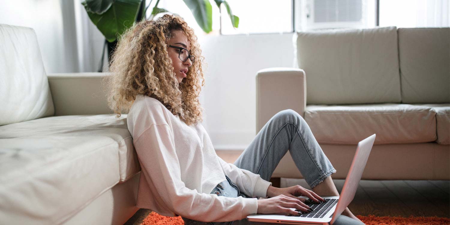 A woman sitting on the floor using her computer