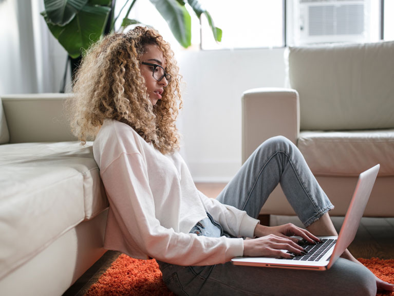 A woman sitting on the floor using her computer