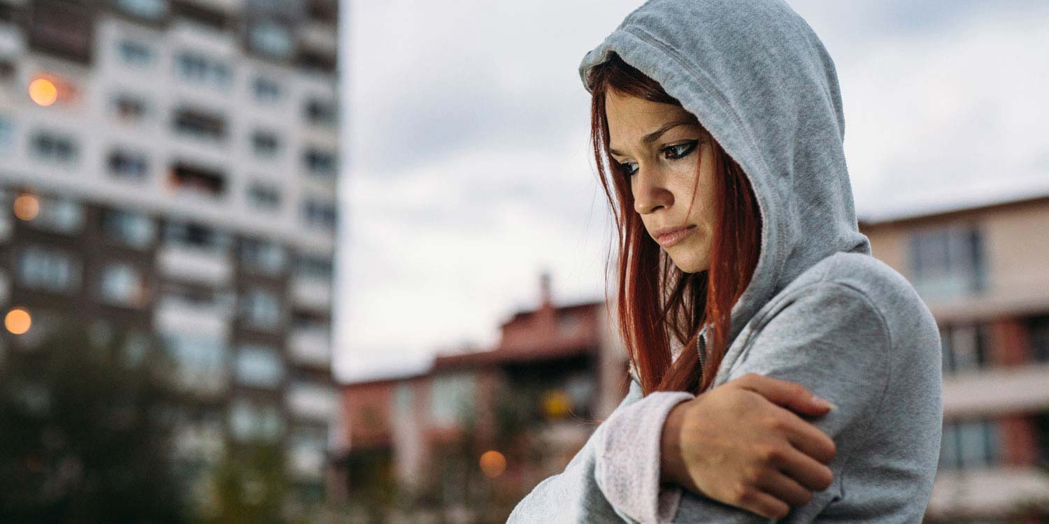 A woman standing in the middle of the city deep in thought