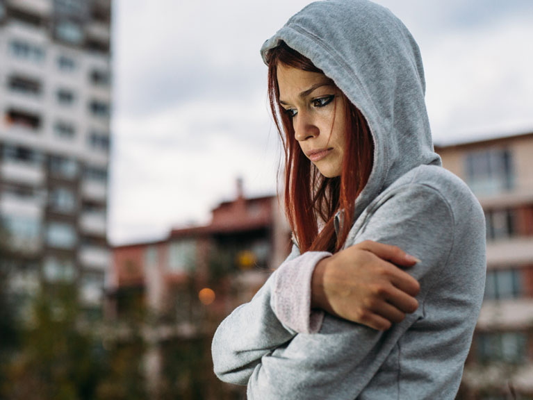 A woman standing in the middle of the city deep in thought