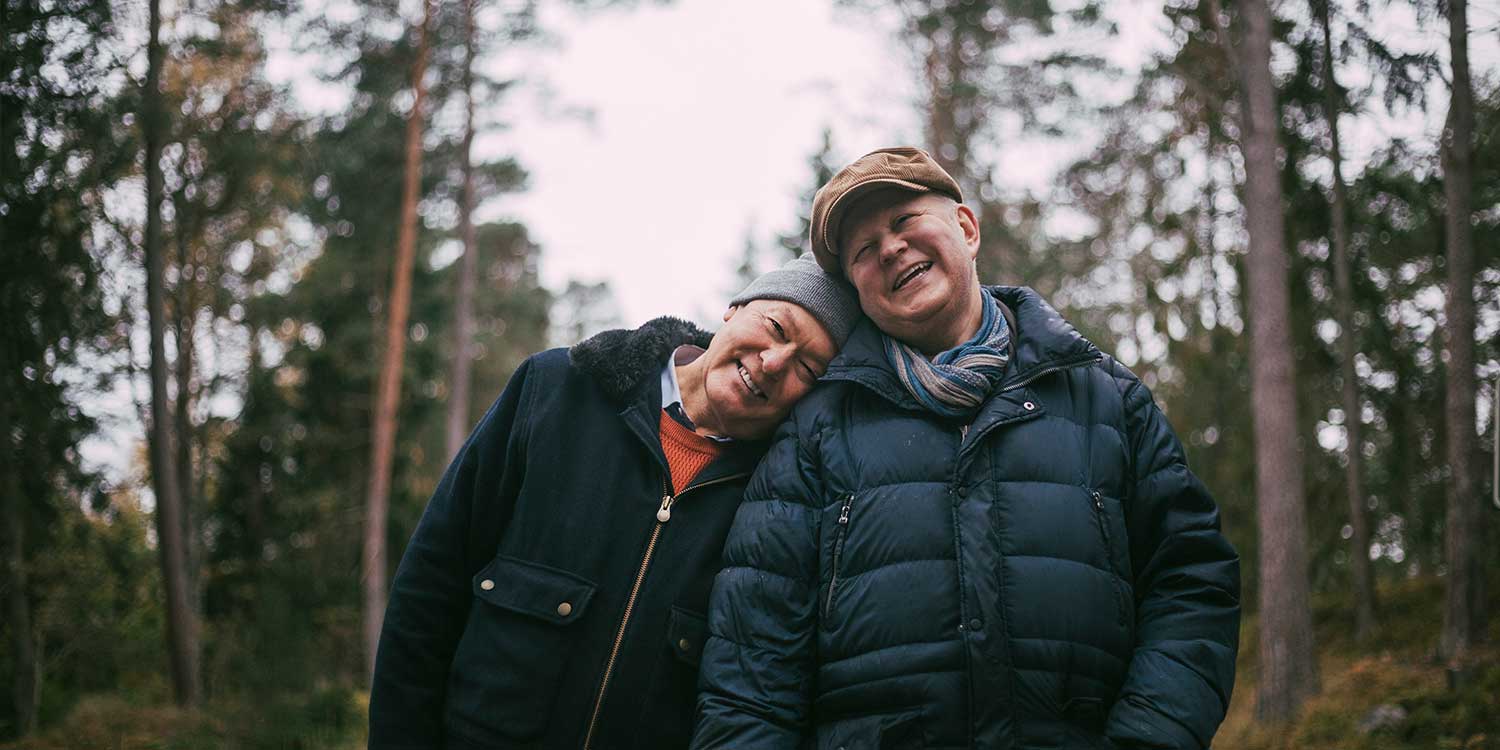 Portrait of smiling gay couple standing in forest
