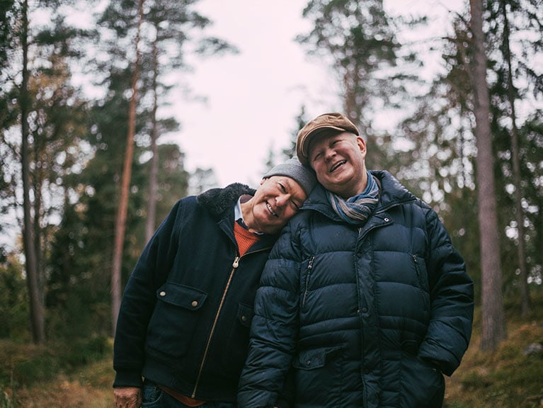 Portrait of smiling gay couple standing in forest