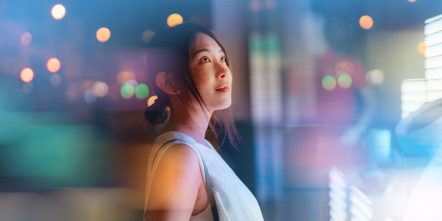 Young Asian businesswoman looking at financial data, standing in front of digital display