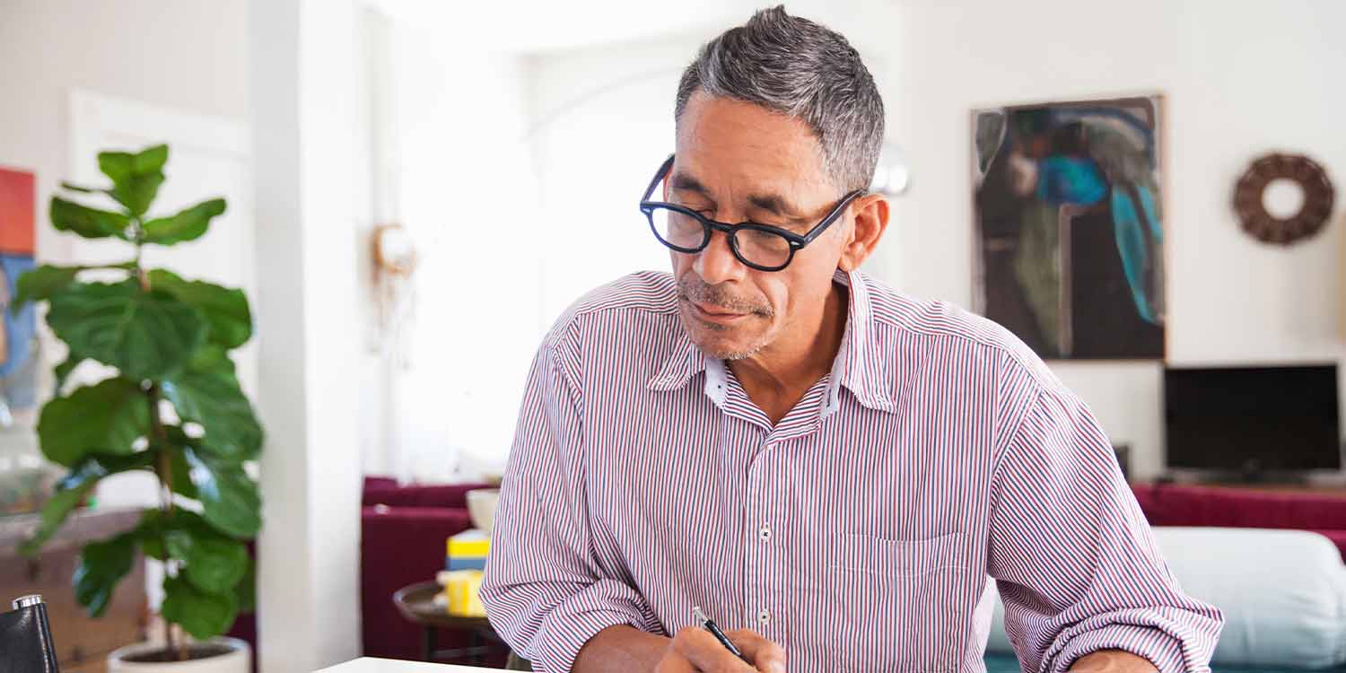 Mature man wearing eyeglasses working on personal finances at home