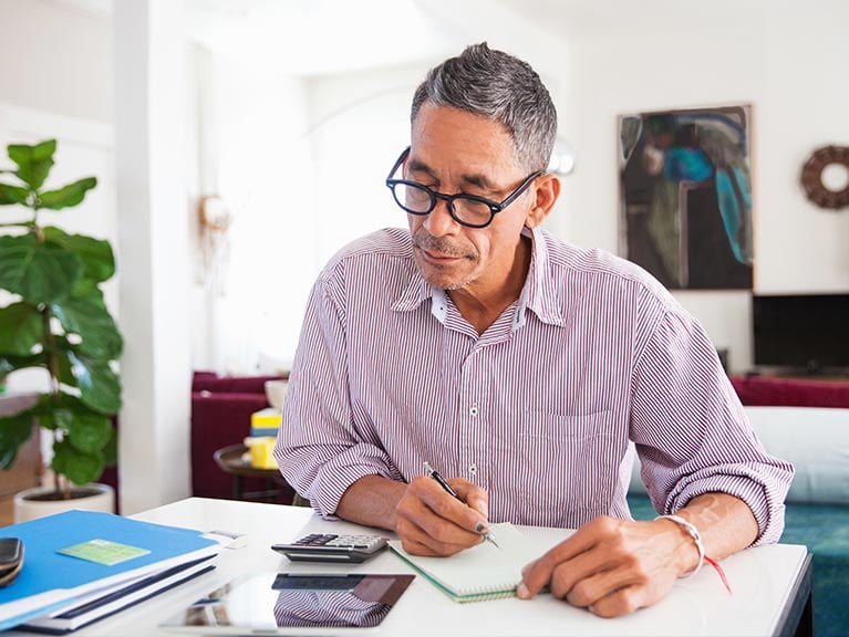 Mature man wearing eyeglasses working on personal finances at home